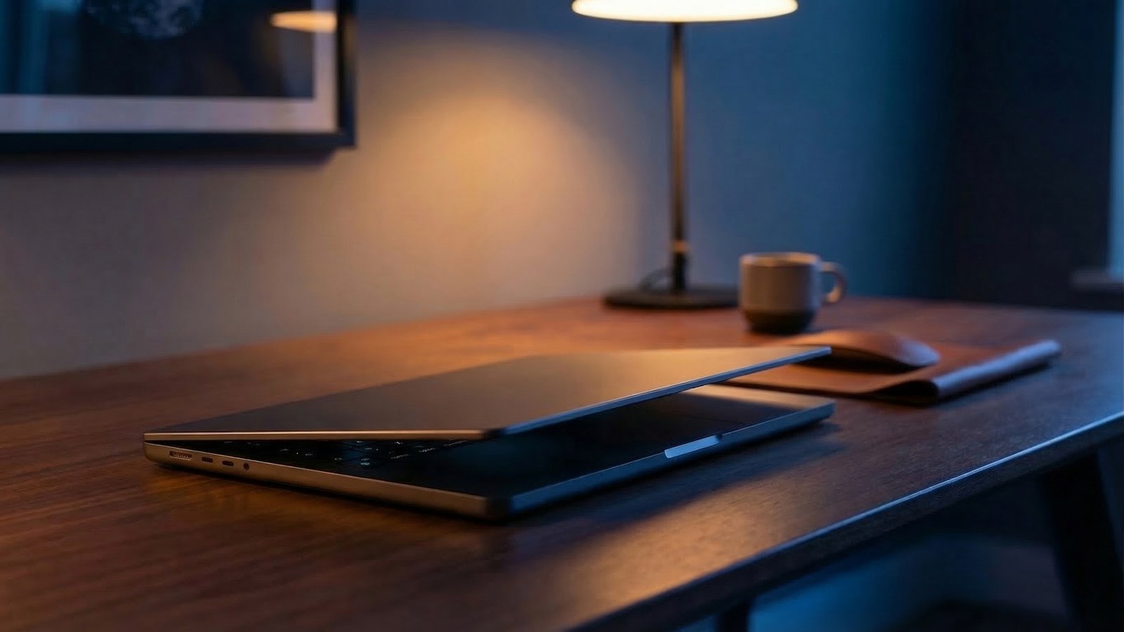 A sleek MacBook Neo on a desk in warm amber and deep navy lighting